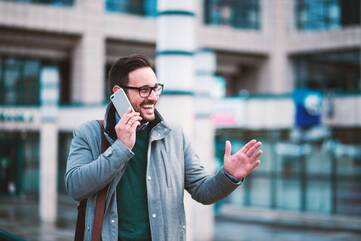 Mann telefoniert mit Handy vor einem Gebäude