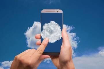 Person hält Handy vor Wolken