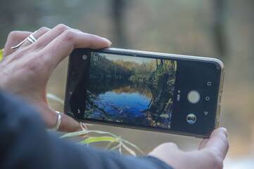 Person macht mit dem Handy ein Foto von einem See