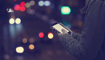 Smartphone gehalten von einem Mann. Straße bei Nacht im Hintergrund