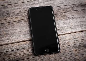 Schwarzes iPhone liegt auf Holzuntergrund