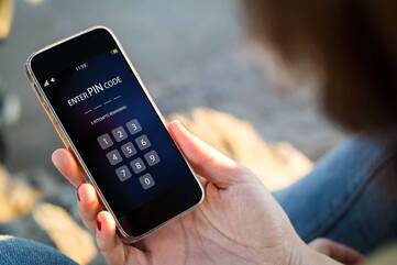 Person guckt auf die Pin-Eingabe eines gesperrten iPhones
