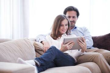 Frau sitzt mit Mann auf dem Sofa und hält Lenovo Tab P10 in der Hand.