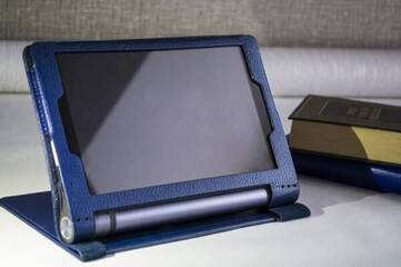 Das Lenovo Yoga Smart Tab befindet sich in einer Hülle und steht neben Büchern.