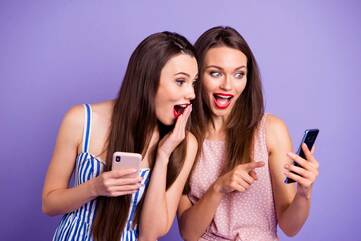 zwei Frauen halten ihr Smartphone in der Hand und gucken schockiert