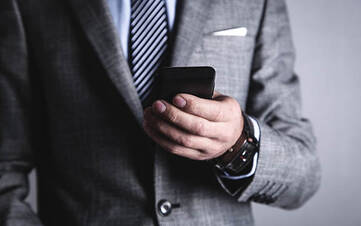 Business-Mann hält ein Smartphone in der linken Hand.