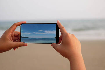 Smartphone wird quer gehalten um ein Foto vom Strand zu machen