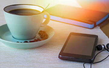 Smartphone liegt auf einem Tisch neben Kaffee und Notizbuch