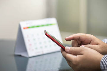 Smartphone wird am Tisch vor einem Tischkalendar bedient