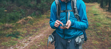 Hiker bedient Smartphone in freier Natur