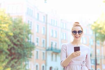 Frau mit Sonnenbrille hält Smartphone in der Hand