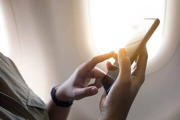 Frau bedient Smartphone im Flugzeug