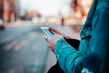 Frau hält Smartphone in beiden Händen auf der Straße