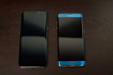 Zwei Samsung Galaxy liegen mit dem Display nach oben auf einem Holzuntergrund