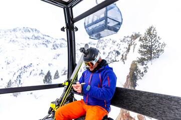 Person guckt im Skilift auf ihr Smartphone