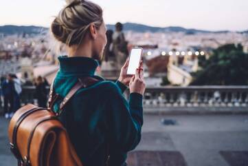 Mit der Aussicht auf eine Stadt bedient eine Frau ihr Smartphone