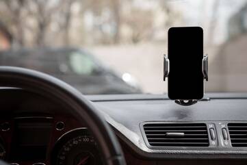 Smartphone in einer Smartphonehalterung an der Windschutzscheibe im Auto