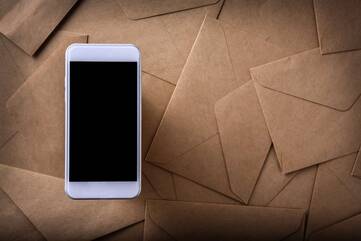 Ein ausgeschaltetes Smartphone liegt auf einer Vielzahl von Briefen