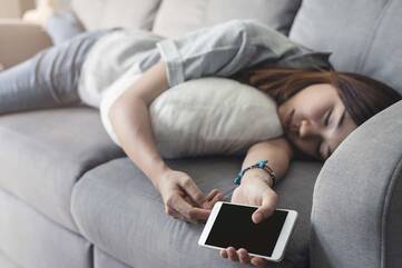 Schlafende Person hält Smartphone in der Hand