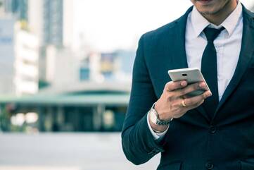 Business Mann tippt im Freien eine SMS auf seinem Smartphone.