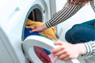 Person holt Wäsche aus der Waschmaschine