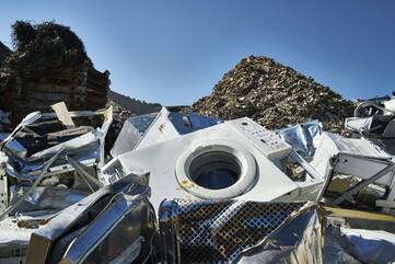 Kaputte Waschmaschine liegt auf Müllhaufen