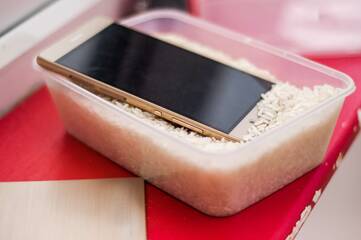 Smartphone liegt in einer Box mit Reis