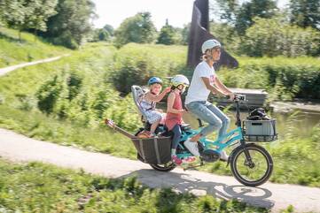 Eine Frau fährt mit ihren Kindern Fahrrad.