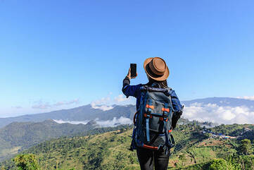 Person hält Smartphone auf einem Berggipfel