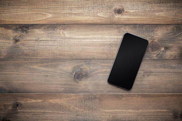 Schwarzes Smartphone liegt auf einem Holztisch