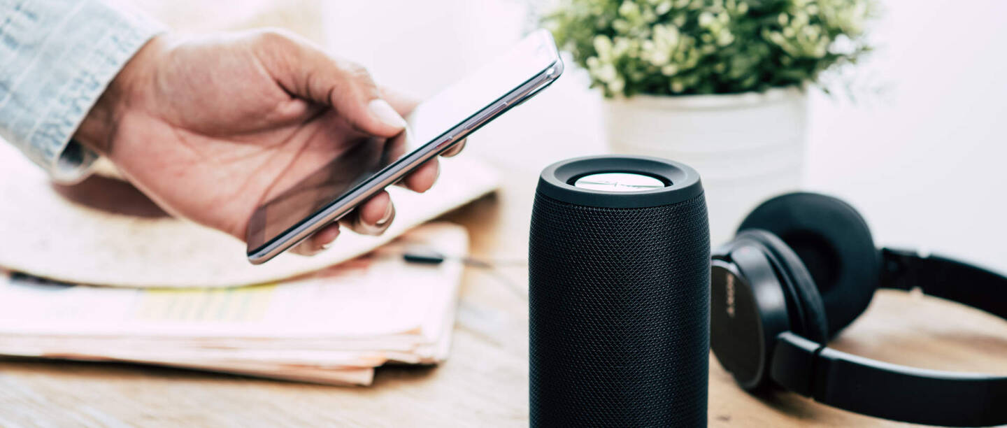 Eine Person verbindet das Handy mit einer Bluetooth-Box und Kopfhörern.