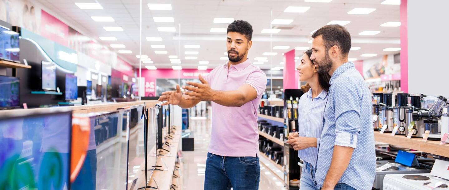 Ein paar in einem Elektronikgeschäft wird von einem Haendler beraten