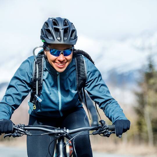 Frontale Ansicht einer lächelnden Fahrradfahrerin in Winterkleidung