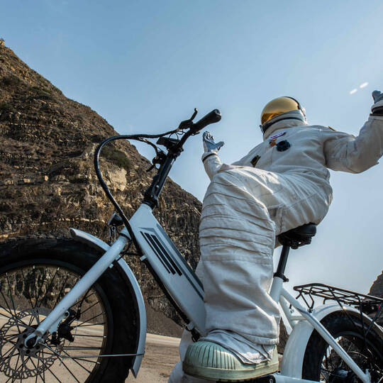 Astronaut sitzt auf einem Fahrrads mit Metallreifen