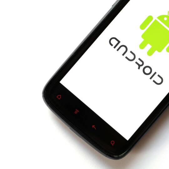 Ein schwarzes Handy mit Android Logo liegt auf einem weißen Hintergrund