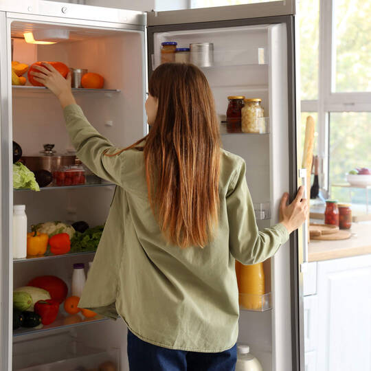 Eine Frau steht vor ihrem Kühlschrank. 
