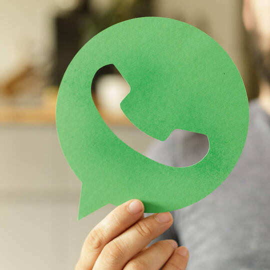 Ein Mann hält ein Icon von einer Messenger-App in der Hand.