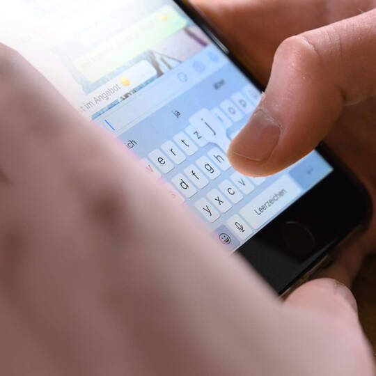 Ein Mann tippt auf seinem Smartphone in der WhatsApp-App.