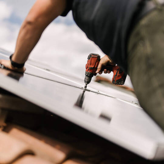 Eine Person schraubt ein Solarpanel fest. 
