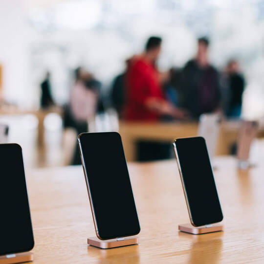 Mehrere iPhones stehen ausgestellt auf einem Tisch.