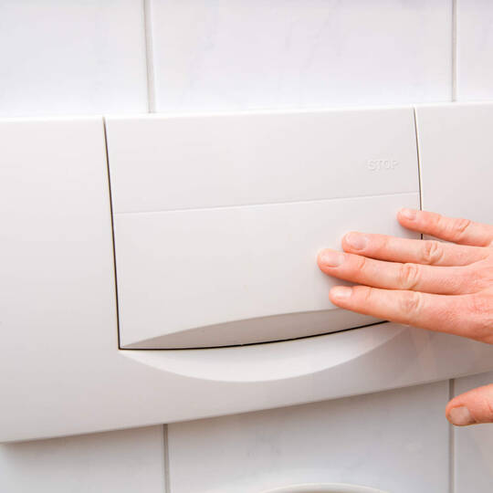 Eine Person drückt auf die Toilettenspülung.