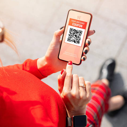 Eine Frau guckt sich auf ihrem Smartphone einen Coupon an.