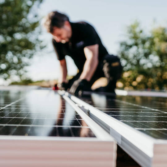 Ein Mann kontrolliert eine Solaranlage auf dem Dach.