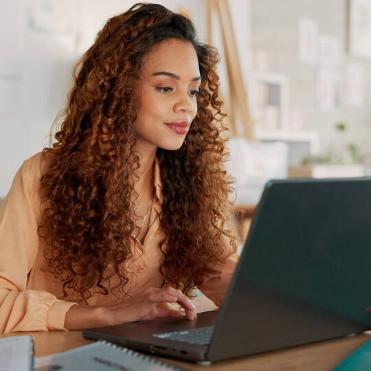 Eine Frau sitzt vor ihrem Laptop.