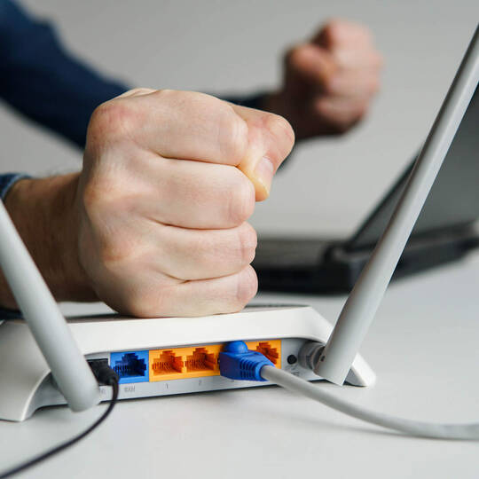 Eine Person haut auf den WLAN-Router.