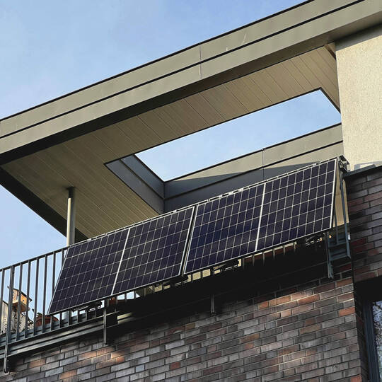 Ein Balkonkraftwerk ist an einem Balkon im oberstem Geschoss eines Mehrfamilienhauses montiert.