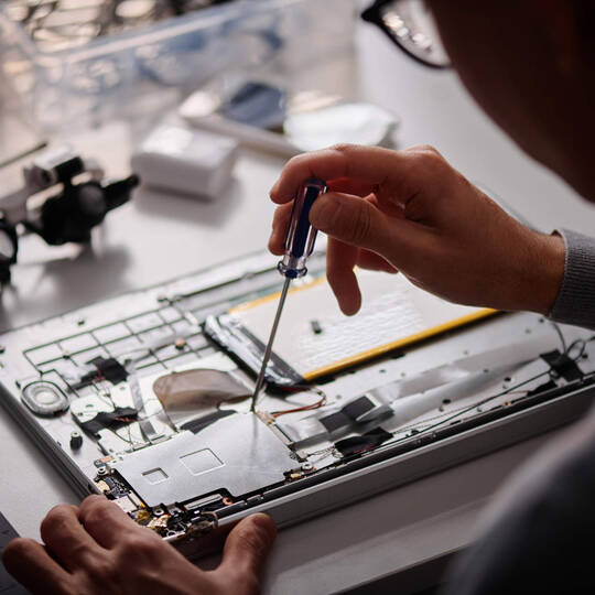 Ein Mann schraubt mit einem Schraubenzieher an einer intern verbauten Festplatte herum.