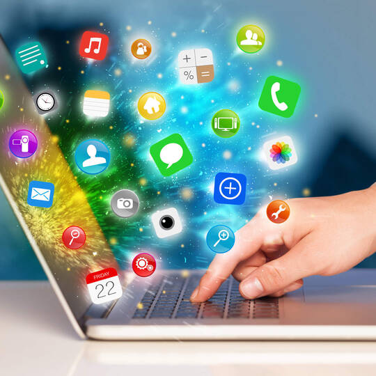 Über der Tastatur eines Laptops schweben mehrere Icons von unterschiedlichen Programme und Apps.