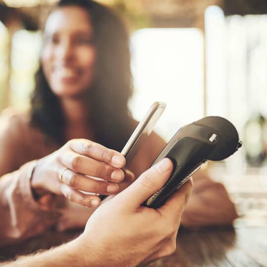 Eine Frau hält ihr Handy an ein Kartenlesegerät.