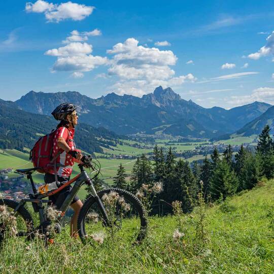 Frau schiebt E-Mountainbike durch die Berge